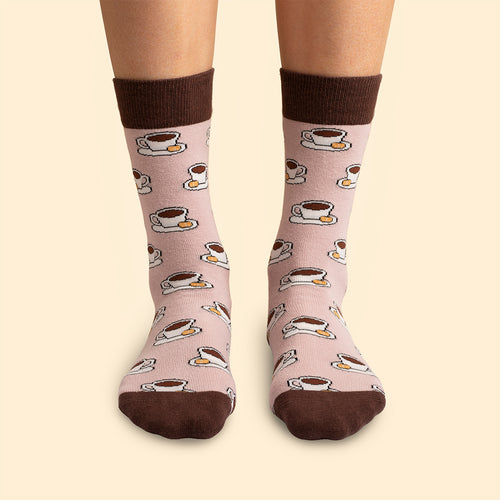 Pink Svenskhusman socks with a pattern of coffee cups and cookies worn on feet.