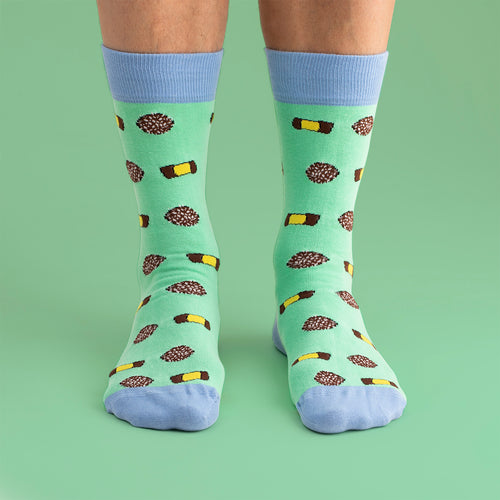 Light green Svenskhusman socks with a pattern of Swedish punsch rolls and chocolate balls and blue accents.