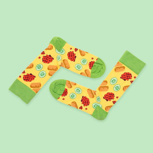 Yellow and green socks featuring a pattern of Swedish cabbage rolls and lingonberries from Svenskhusman.