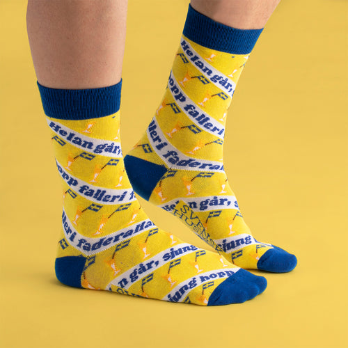 Gula strumpor med blå detaljer prydda med snapsvisan Helan går och små nubbeglas från Svenskhusman.