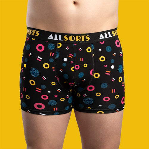 Svarta kalsonger med mönster av ALLSORTS lakritskonfekt på en herrmodell mot en gul bakgrund från Svenskhusman.