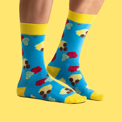 Blue socks with a meatball and mashed potato pattern worn on feet against a yellow background.