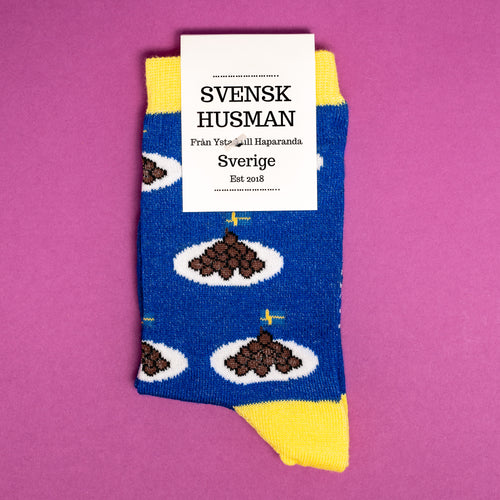 Blå barnstrumpor mönstrade med köttbullar på tallrik och svenska flaggor från märket Svenskhusman.