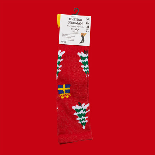 Röda stödstrumpor med motiv av snöiga julgranar och blågula paket från Svenskhusman.