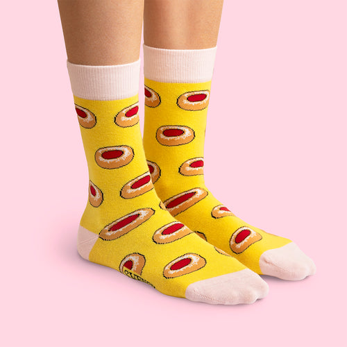 Yellow socks with a raspberry cave cookie pattern on a pink background from Svenskhusman.