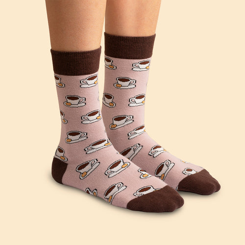 Pink socks with a coffee cup and cookie pattern, featuring brown accents, shown on feet - Svenskhusman