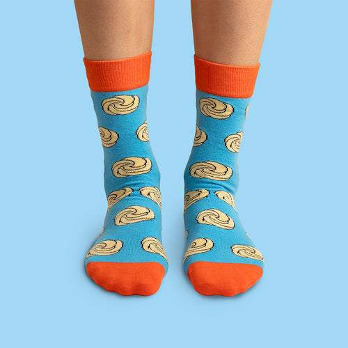 Blue sugar pretzel patterned socks with orange cuffs and toes, worn on feet by Svenskhusman.