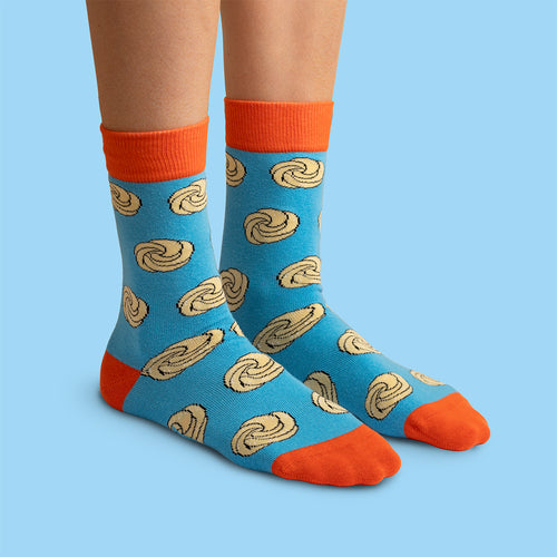 Blue Svenskhusman socks with a sugar pretzel pattern and orange accents against a light blue background.