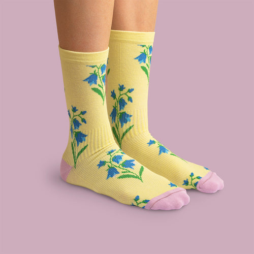 Yellow compression socks with bluebell motifs, pink toe and heel on a purple background by Svenskhusman