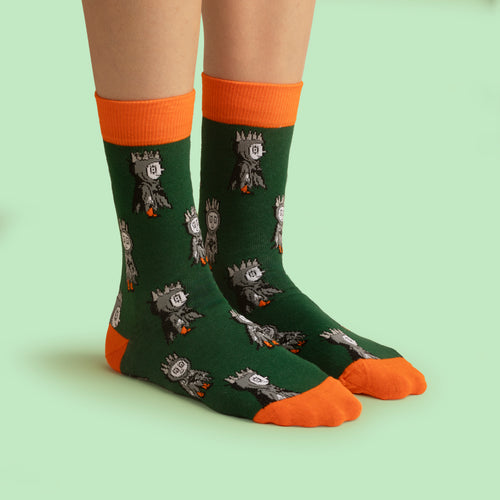 Gröna strumpor med Labolina Halloween-motiv och orange mudd samt tå från Svenskhusman på en person.
