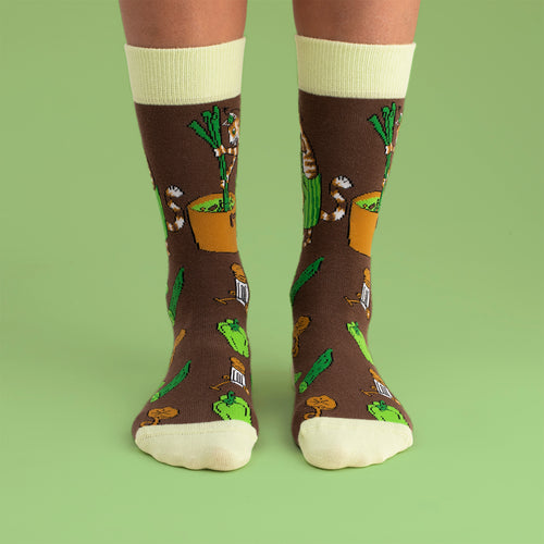Barnstrumpor i brunt med Findus och mönster av grönsakssoppa från Svenskhusman på en grön bakgrund.