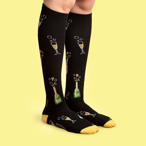 Svarta stödstrumpor med mönster av champagneflaskor och glas från märket Svenskhusman.