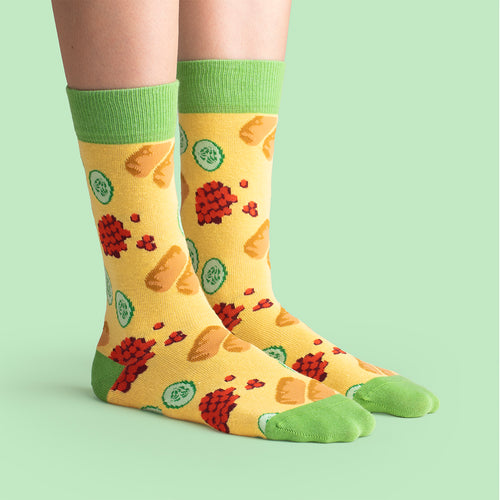 Yellow socks with patterns of cabbage rolls, lingonberries, and pickled cucumber by Svenskhusman.