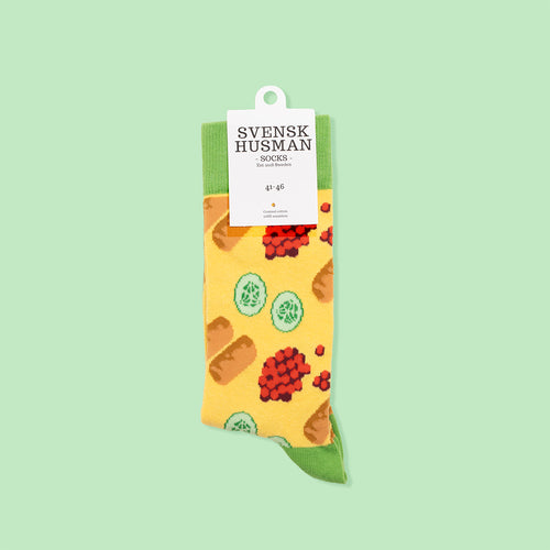 Yellow and green cotton socks featuring a pattern of cabbage rolls and lingonberries by Svenskhusman.