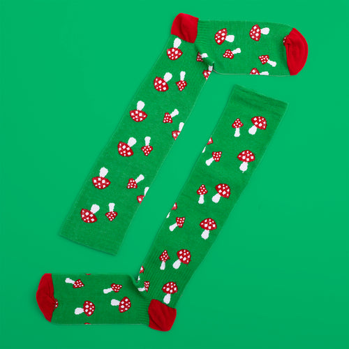 Green support socks with a red fly agaric mushroom pattern on a green background by Svenskhusman.