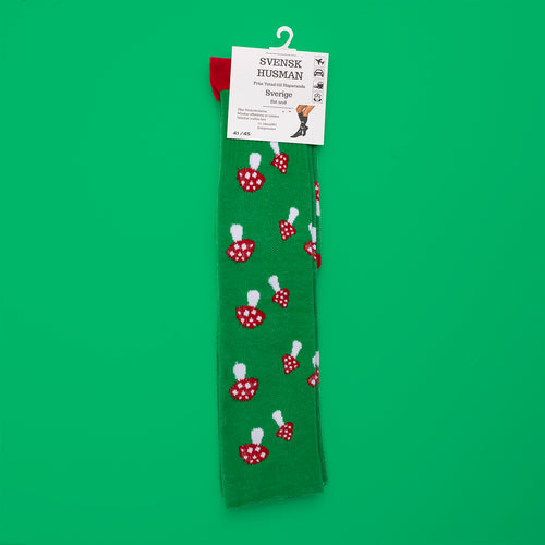 Green support socks with a fly agaric pattern and red heels by Svenskhusman on a green background.