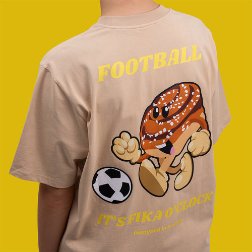 Beige oversize t-shirt i bomull med tryck av en fotbollsspelande kanelbulle på ryggen - Svenskhusman