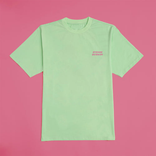 Hellgrünes Surf-Staubsauger Baumwoll-T-Shirt mit Svenskhusman-Logo auf der Brust vor rosa Hintergrund.