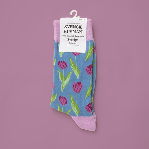 Hellblaue Socken mit farbenfrohen rosa Tulpen und grünen Blättern von Svenskhusman.