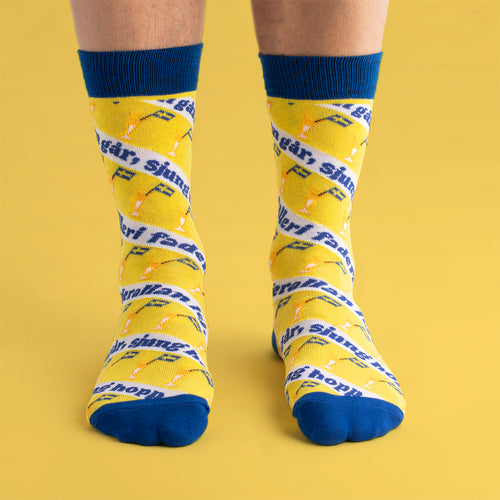 Gelbe und blaue Socken von Svenskhusman mit Motiven von Schnapsgläsern und dem Liedtext „Helan går“.