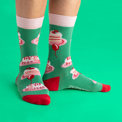 Green socks with a playful cream cake pattern, pink cuffs and red toes from Svenskhusman.