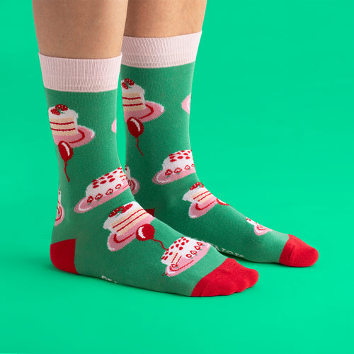 Green cotton socks featuring a cream cake pattern, pink cuffs, and red details by Svenskhusman.