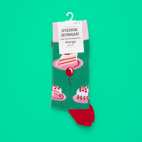 Green cotton socks with a pattern of classic cream cakes and red details from Svenskhusman.