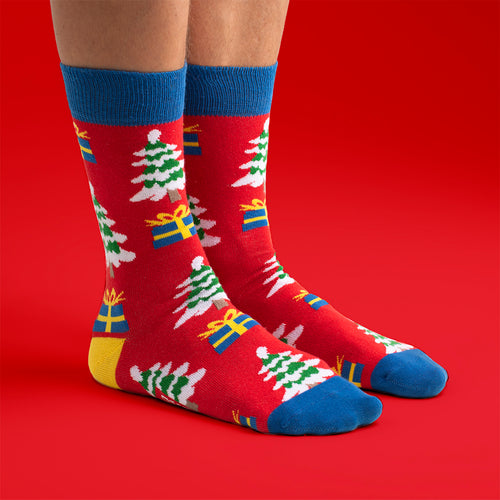 Röda julstrumpor med mönster av snöiga julgranar och färgglada paket från Svenskhusman.