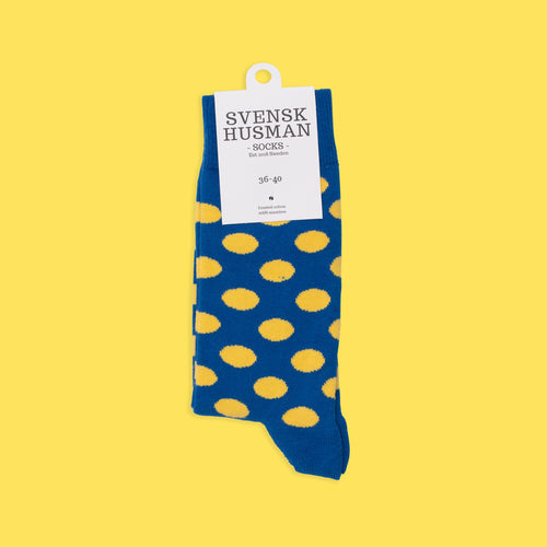 Blau-gelb gepunktete Socken aus weicher gekämmter Baumwolle von Svenskhusman auf gelbem Hintergrund.