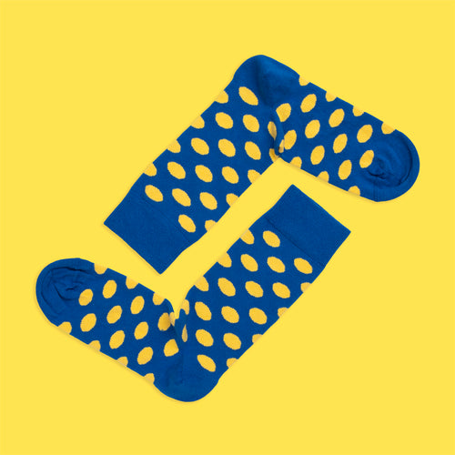 Blau-gelb gepunktete Socken aus weicher gekämmter Baumwolle von Svenskhusman auf gelbem Hintergrund.