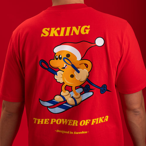 Röd t-shirt med ett lekfullt tryck av en skidåkande lussebulle och texten Skiing från Svenskhusman.