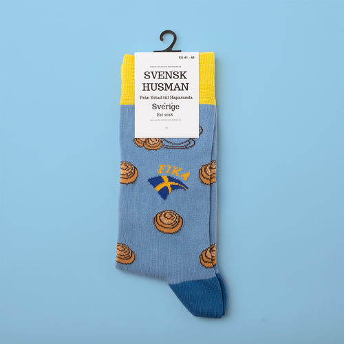 Lyseblå mønstrede sokker med kanelboller, det svenske flag og teksten FIKA fra Svenskhusman.
