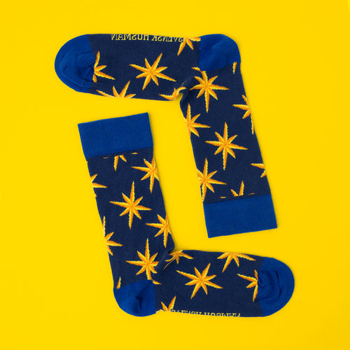Dark blue cotton socks with yellow poinsettia patterns on a vibrant yellow background by Svenskhusman.