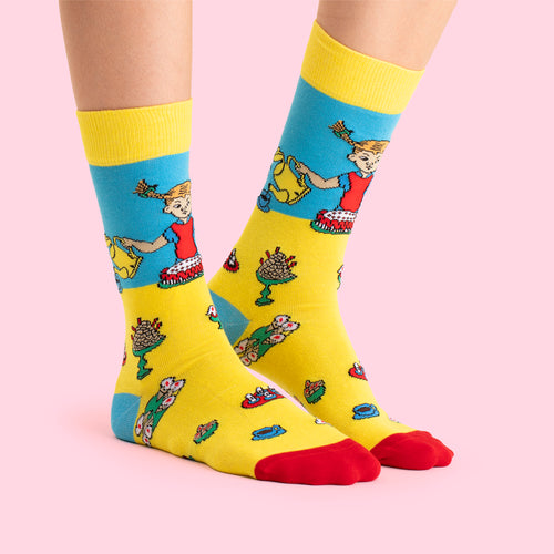 Gula och blå Pippi Kalas-strumpor med motiv av Pippi Långstrump på rosa bakgrund från Svenskhusman.