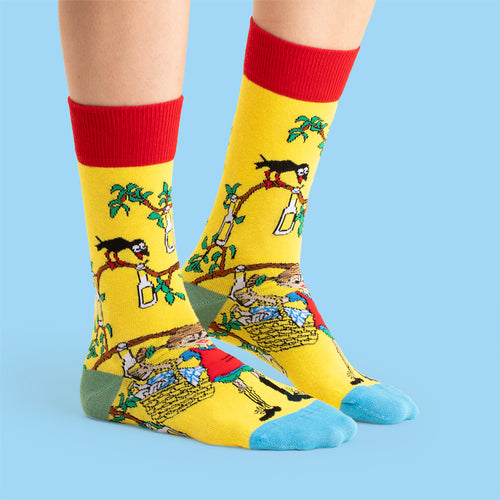 Gelbe Pippi Langstrumpf Socken mit Sockerdricka-Baum-Motiv, roten Bündchen und blauen Zehenspitzen.