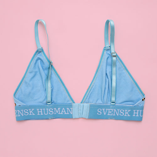 Ljusblå BH i bomull med fika-mönster och textat resårband från Svenskhusman på rosa bakgrund.