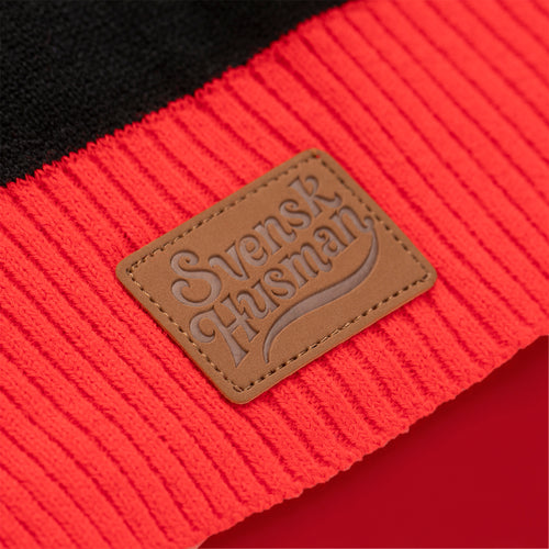 Braunes Leder-Logo-Patch auf rotem Rippbündchen am Polkagris Weihnachtspullover von Svenskhusman.