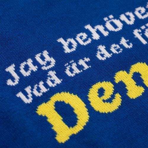 Close-up of a blue knitted Christmas sweater with white and yellow Swedish text by Svenskhusman.