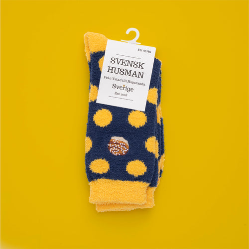 Dark blue and yellow fluffy socks with polka dots and an embroidered cinnamon bun from Svenskhusman.