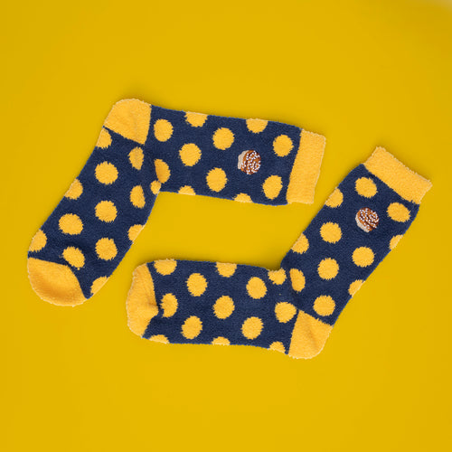 Blue fluffy socks with yellow polka dots and cinnamon buns on a yellow background - Svenskhusman