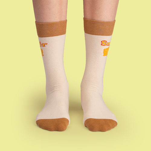 Beige strumpor med texten Smör, gult smörmotiv och bruna detaljer från Svenskhusman.