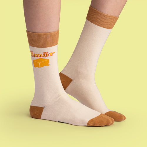 Beigea strumpor med motiv av en gul smörklick och texten Smör, Svenskhusman.