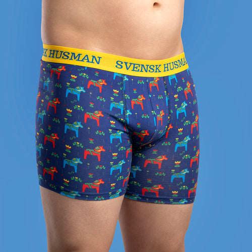 Mörkblå boxerkalsonger med mönster av dalahästar och gult resårband från Svenskhusman på en modell.