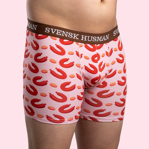 Rosa boxerkalsonger med mönster av falukorvar och brunt resårband, burna av en modell för Svenskhusman.