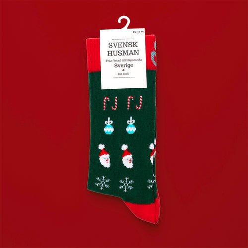 Grüne und rote Weihnachtsstrümpfe mit Motiven von Weihnachtsmännern und Zuckerstangen aus der Serie Dö tomte jävel.