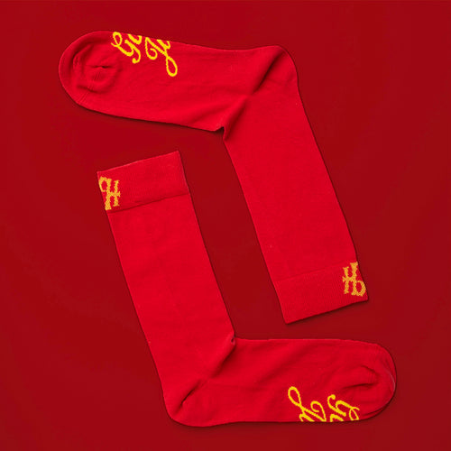 Röda bomullsstrumpor med gul God Jul-text på undersidan från Svenskhusman.