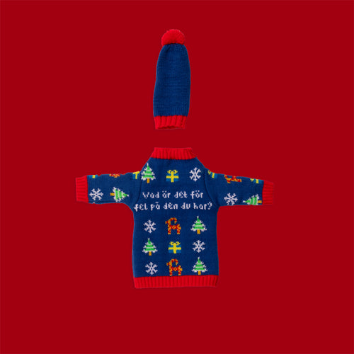 Blue knitted bottle sweater and hat with festive patterns and Swedish text against a red background.