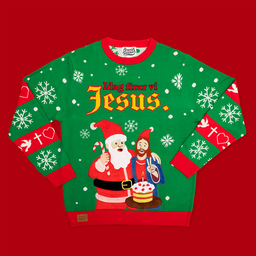Grön jultröja med texten ”Idag firar vi Jesus” och motiv av tomten och Jesus från Svenskhusman på röd bakgrund.