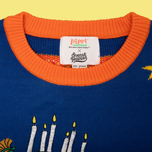 Blå stickad jultröja med orange krage, broderade Lucia-ljus och Pippi Långstrump-etikett från Svenskhusman.