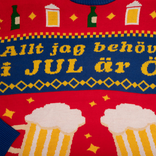 Röd stickad jultröja med julöl-motiv, stora ölglas och gul text från Svenskhusman.